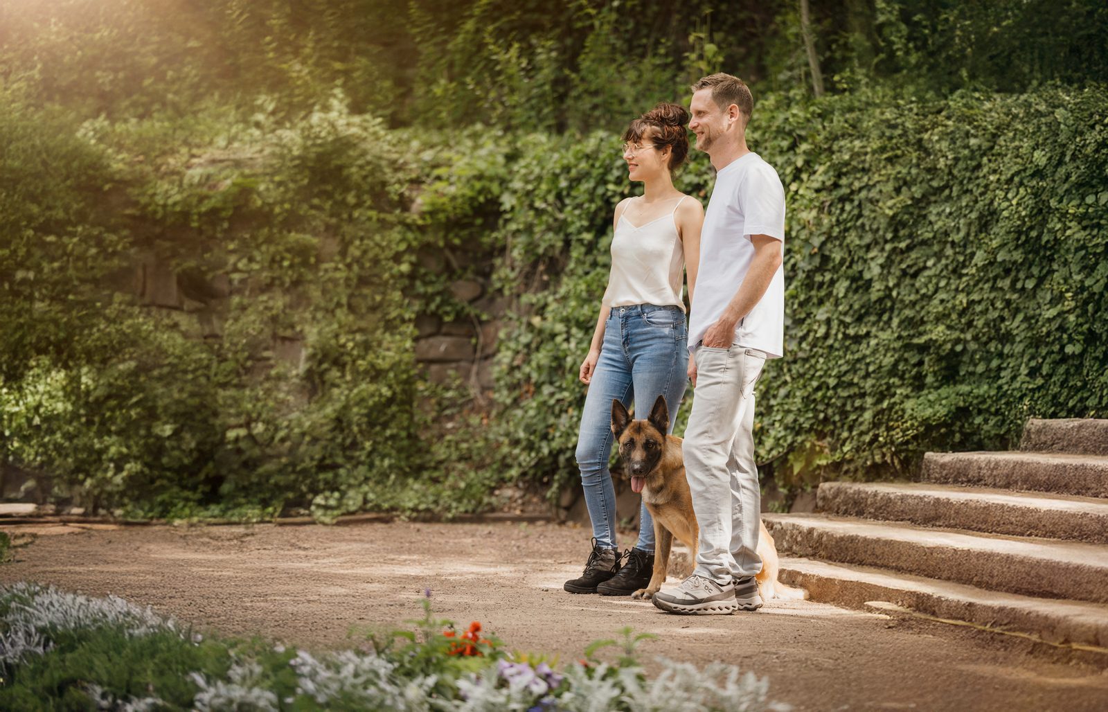 Clemens und Ronja sitzen mit Mali auf einer Treppe im Grünen